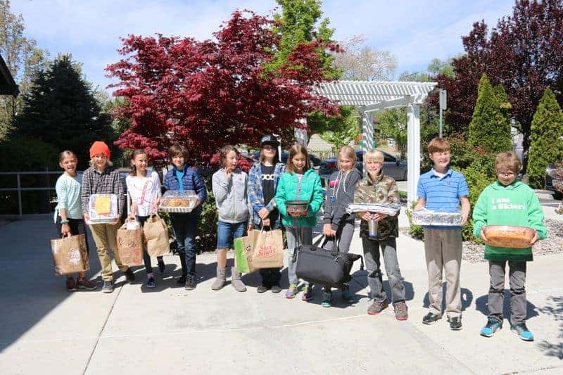 5th graders in a line holding boxes of food