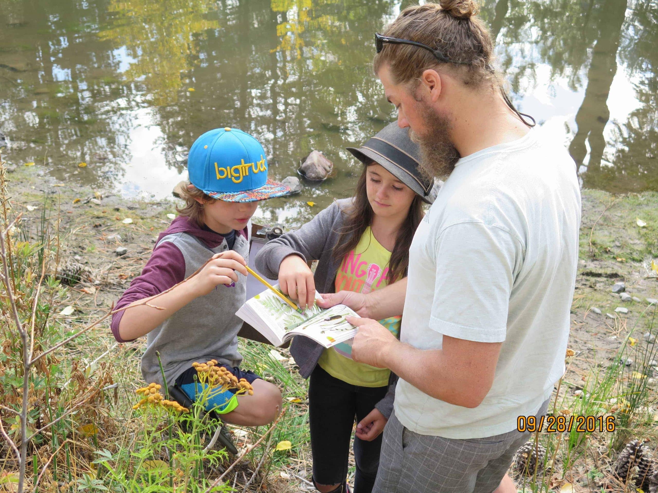 4th graders and their teacher studying a field manual
