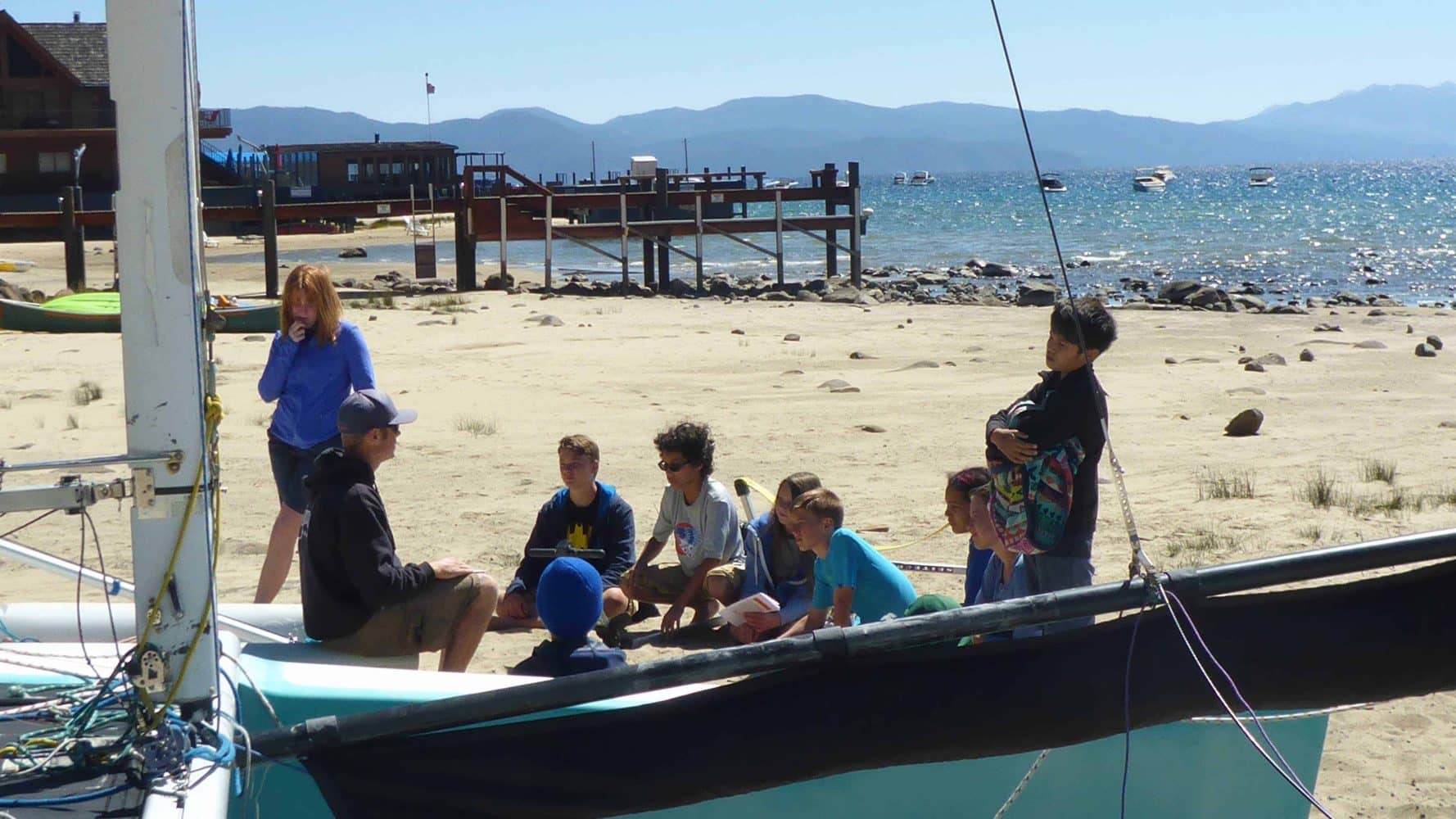 students on shore with their sailboats