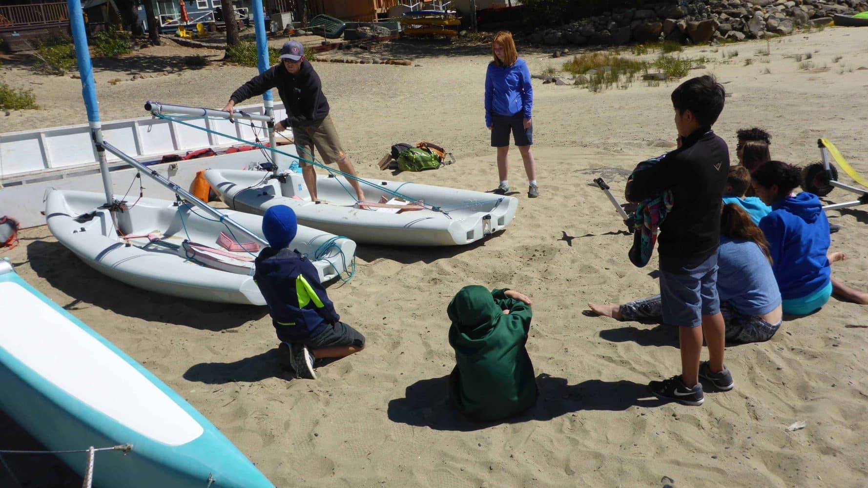 students on shore with their sailboats