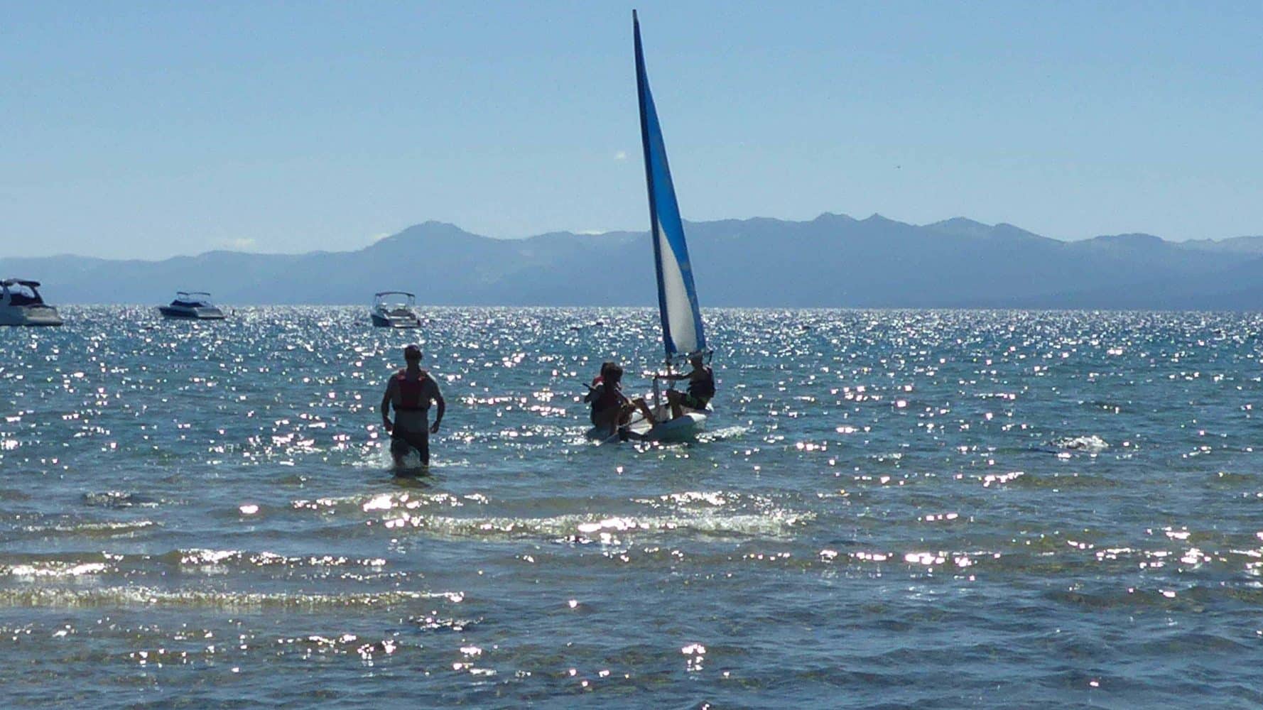 students pushing their boat in from shore
