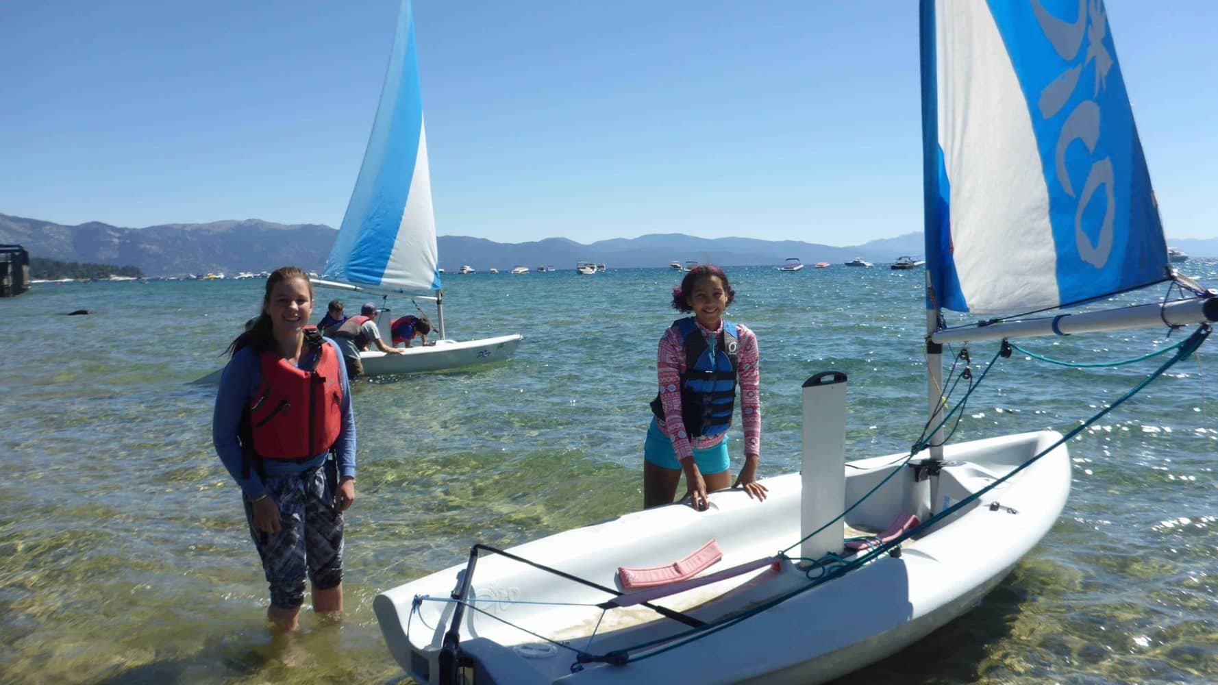 students pushing their boat in from shore