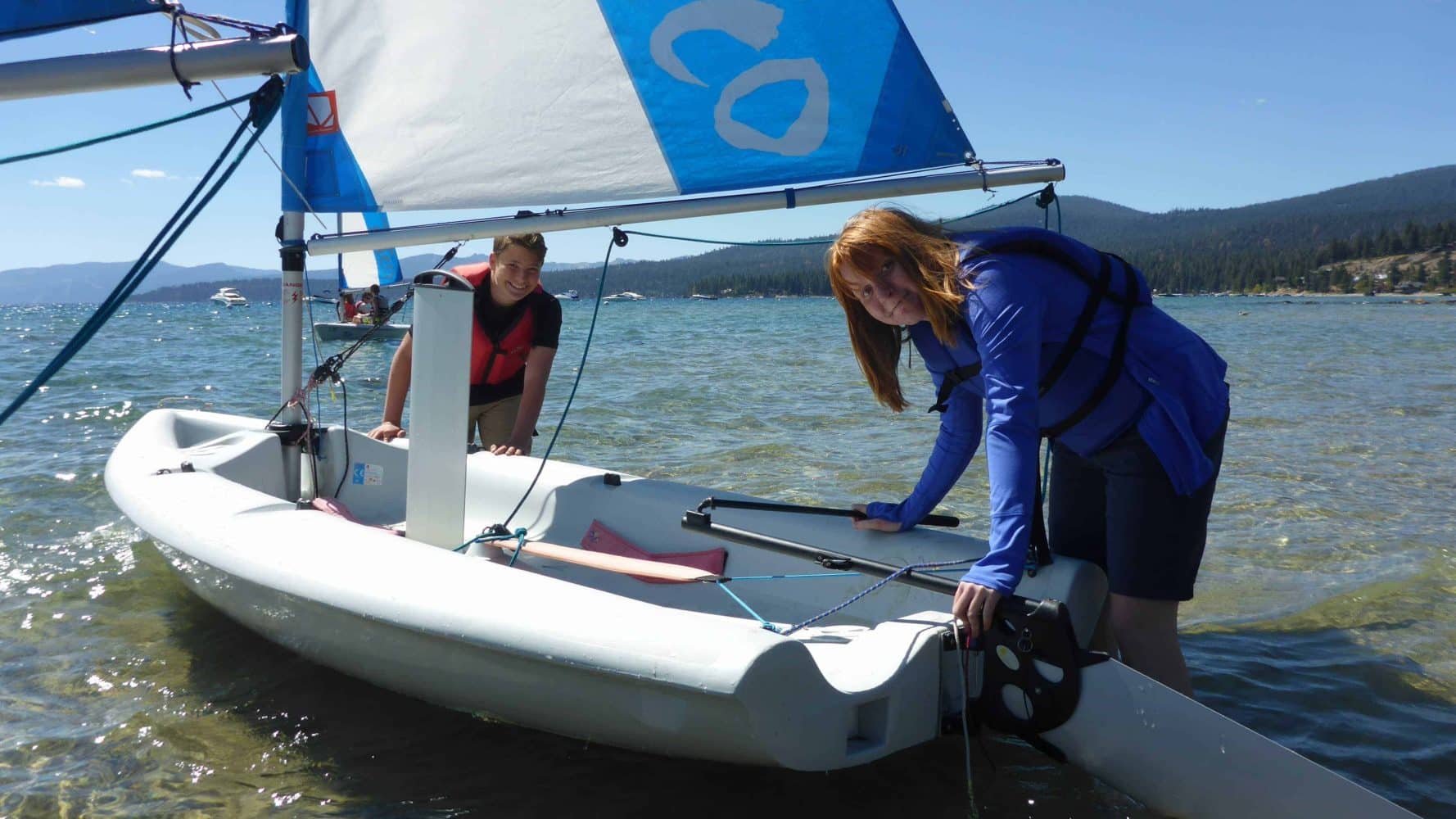 students pushing their boat in from shore
