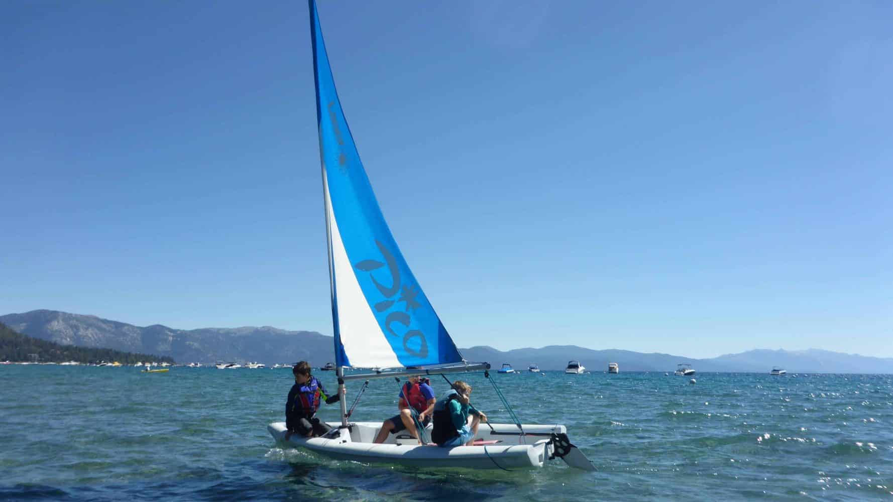 students in the ocean on small sailboats
