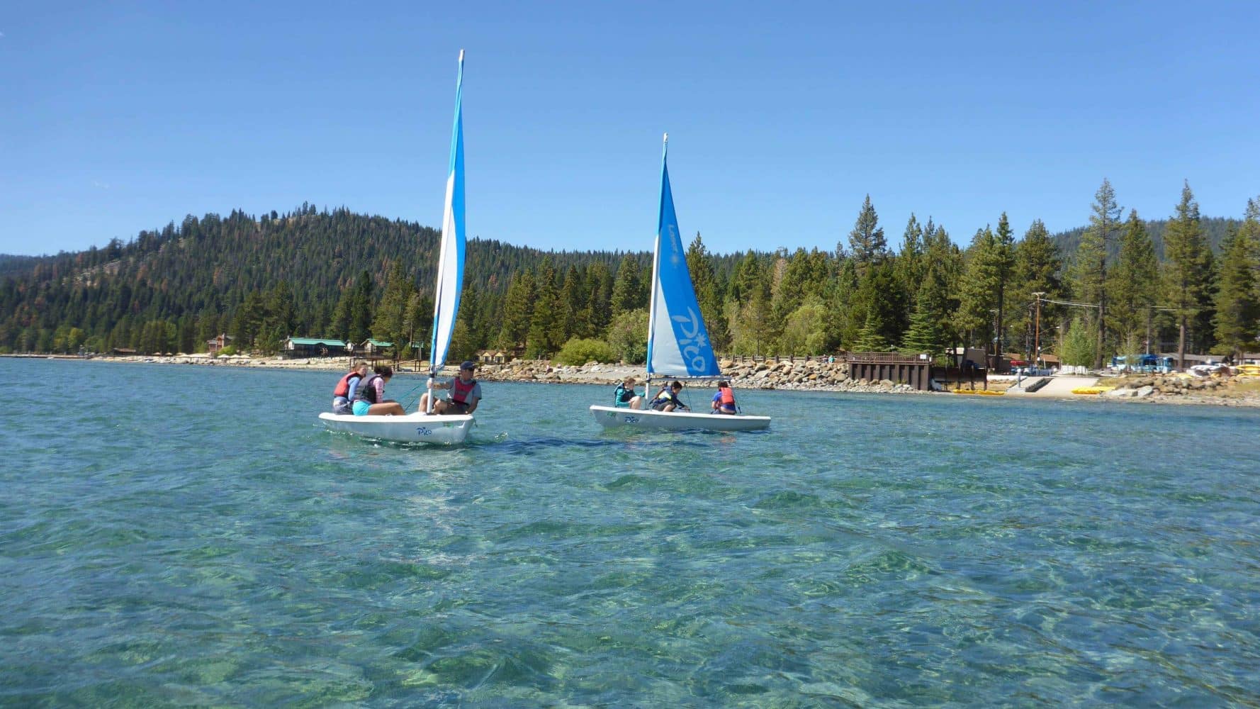 students in the ocean on small sailboats