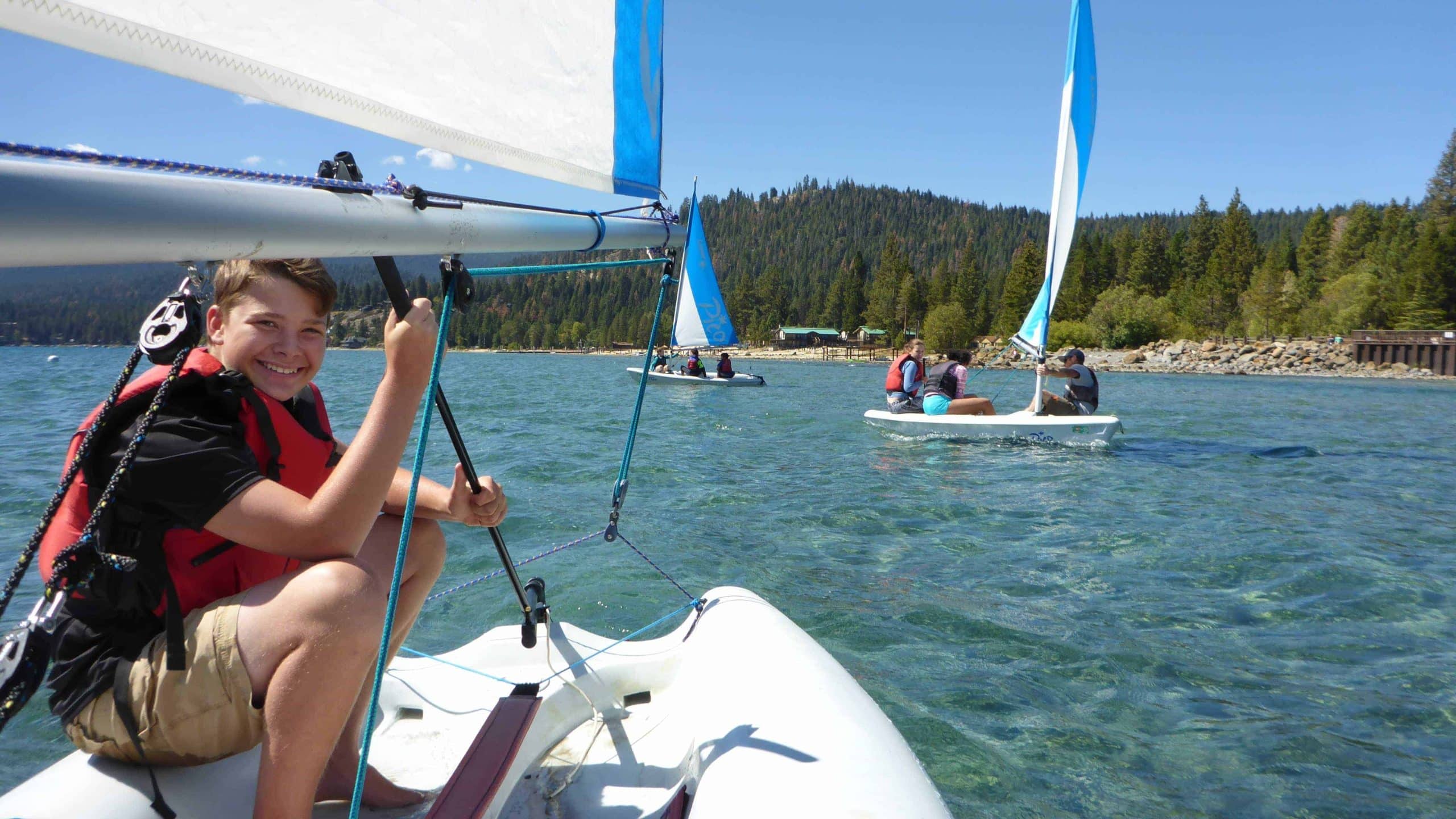 students in the ocean on small sailboats