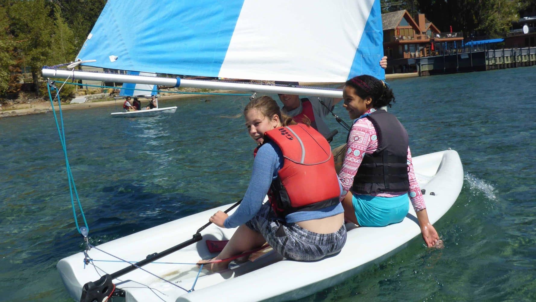 students in the ocean on small sailboats