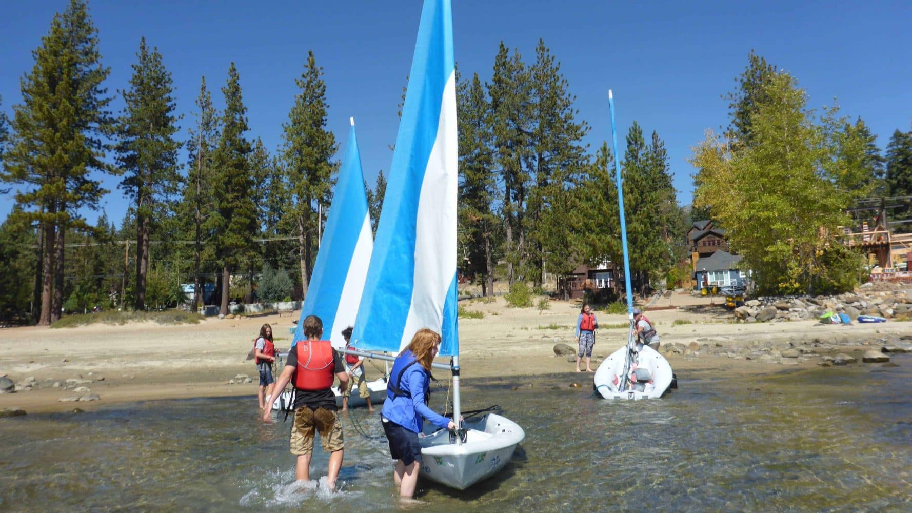students pushing their boat in from shore