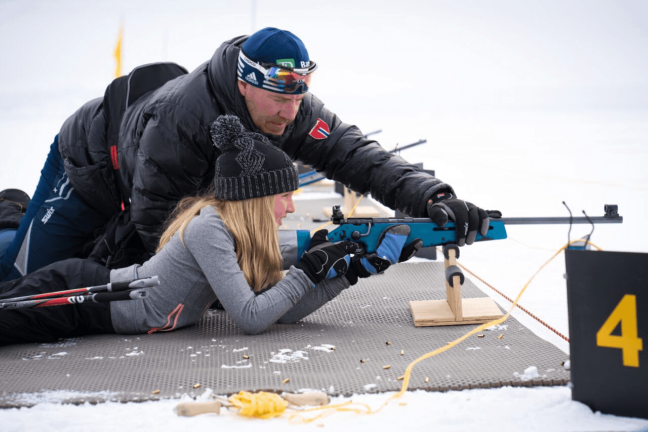 trainer helping biathlete steady her rifle
