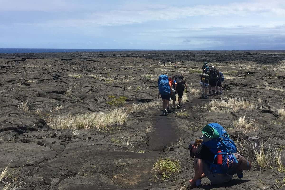 students backpacking across lava fields
