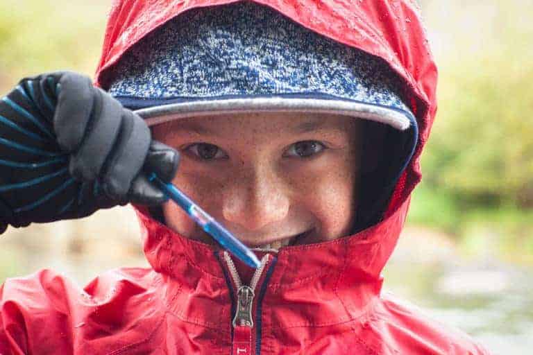 student in a red jacket holding a water sample