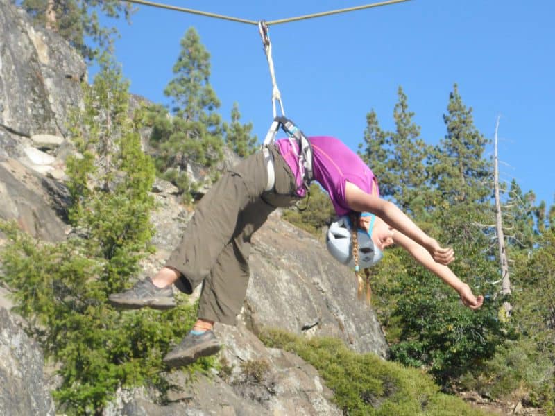 student with a rope harness hanging from a line