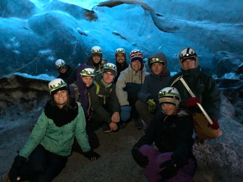 students sitting in a cave having their picture taken
