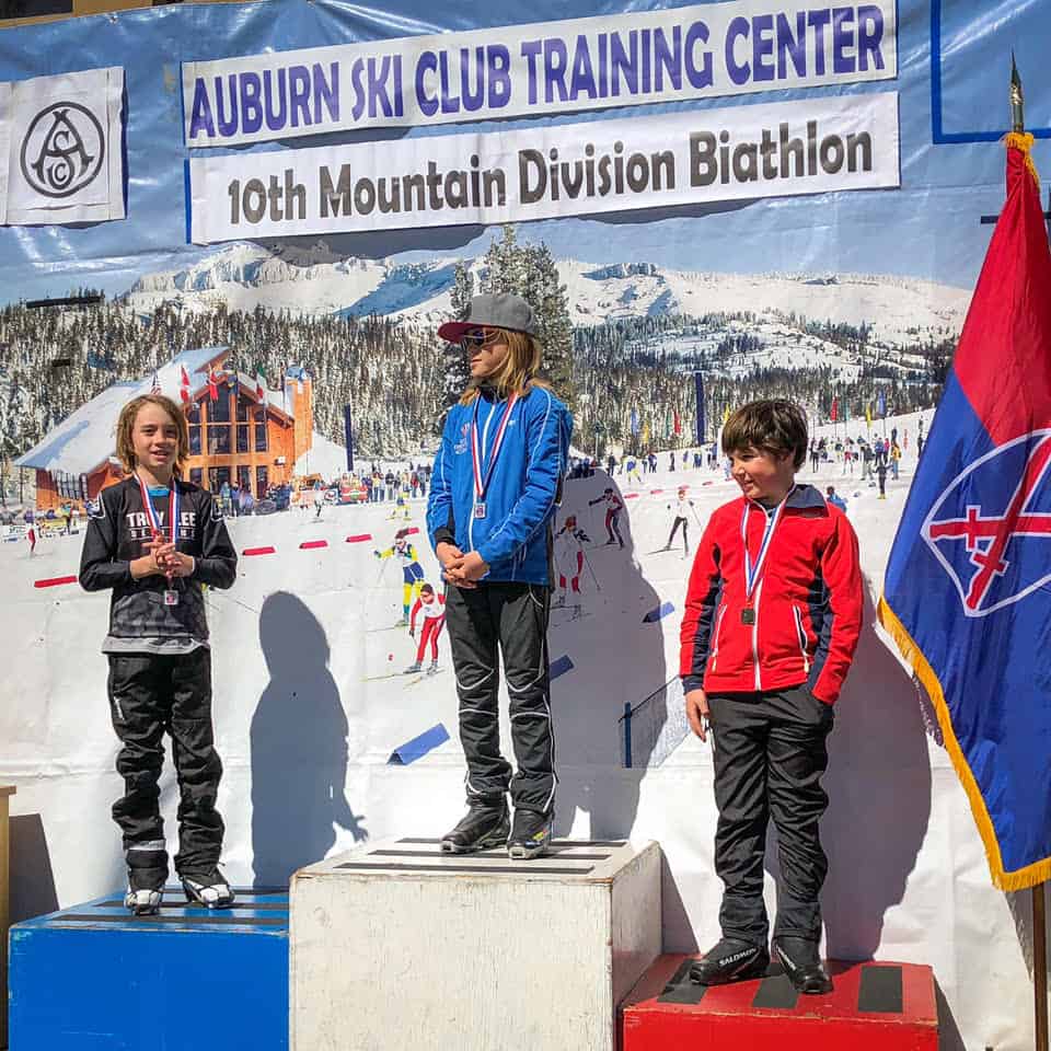 biathletes with medals atop the podium