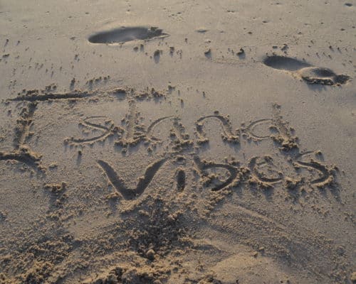 'island vibes' written in the sand