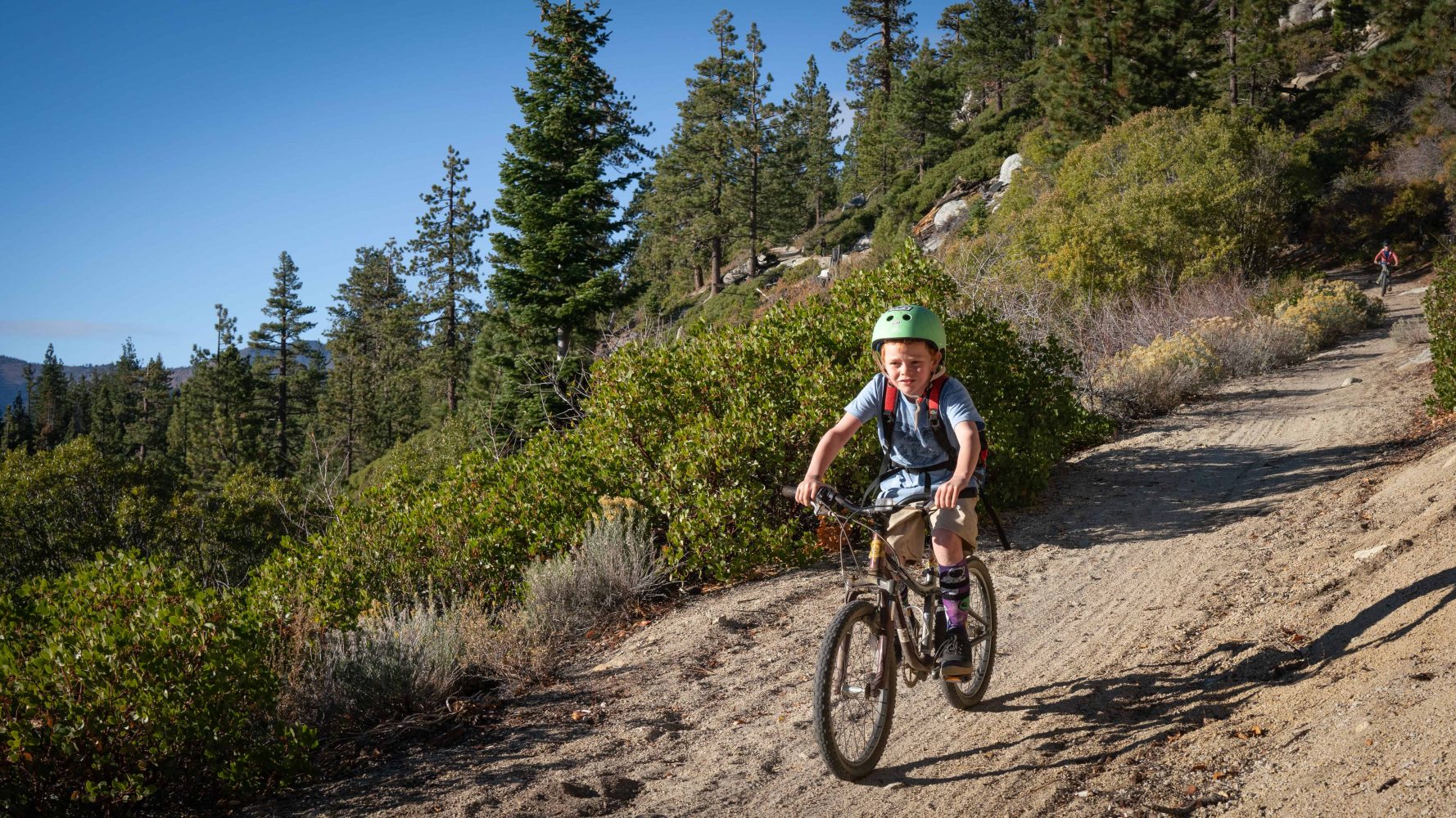 kid with helmet on bike riding down the trail