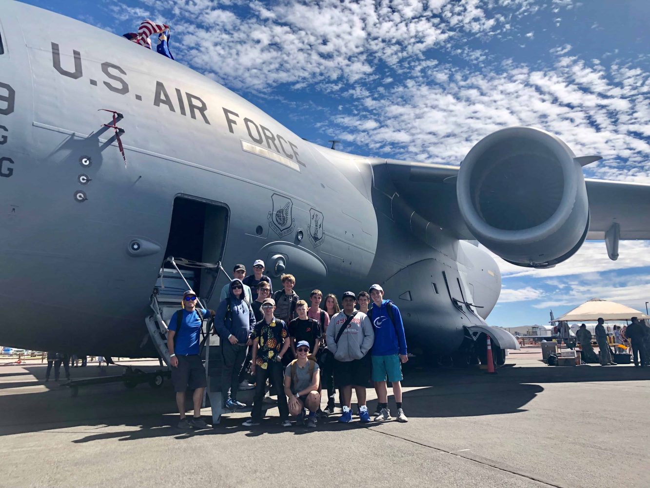 students having their picture taken by an aircraft carrier