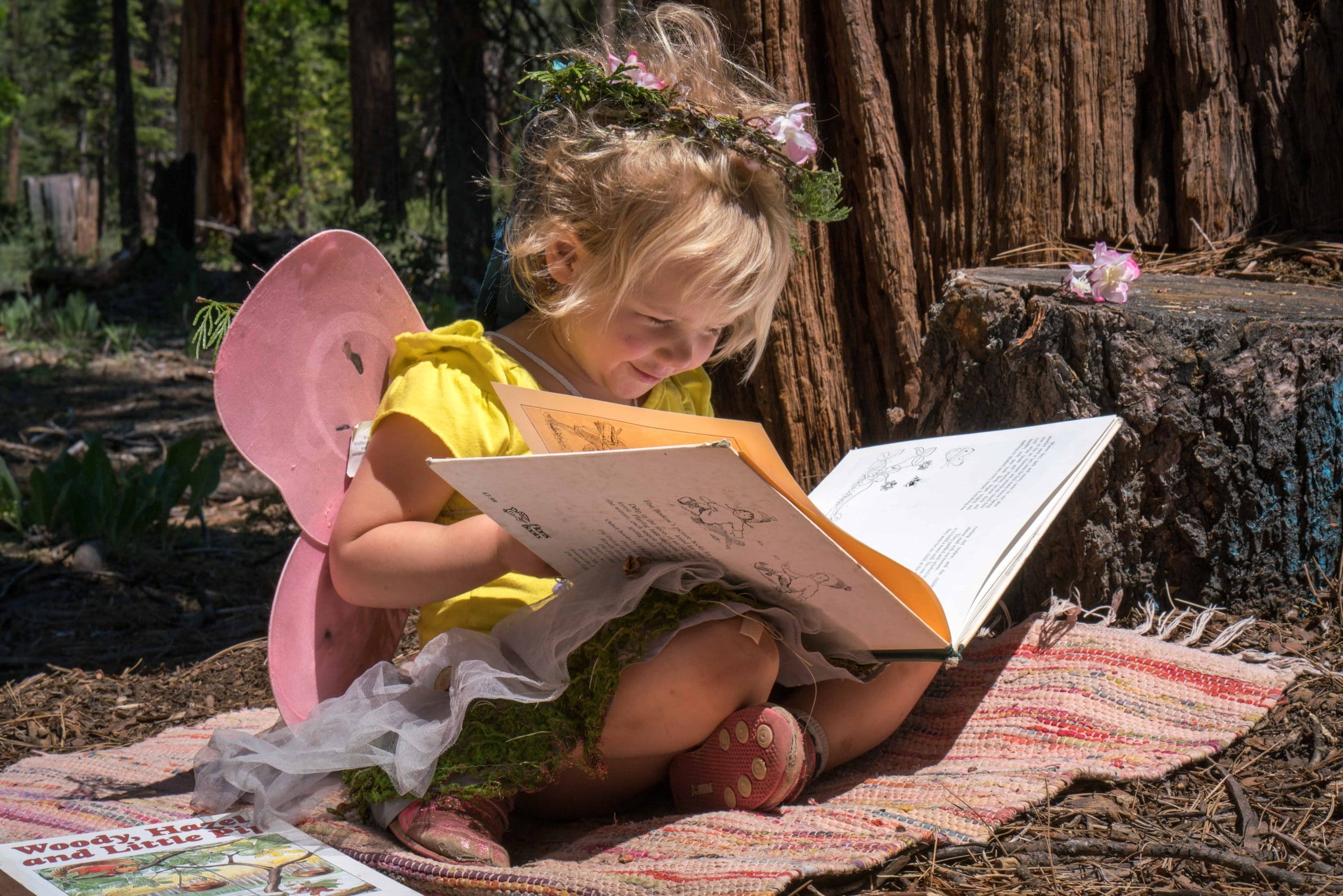 pre-k student in a fairy costume sitting and reading