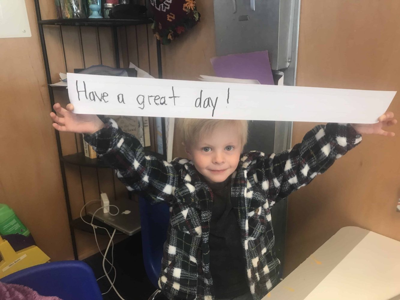 pre-k student holding a sign that reads have a great day