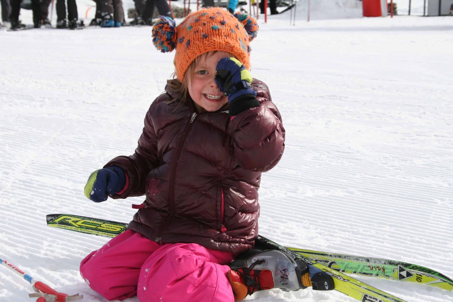 pre-k student with skis kneeling in the snow