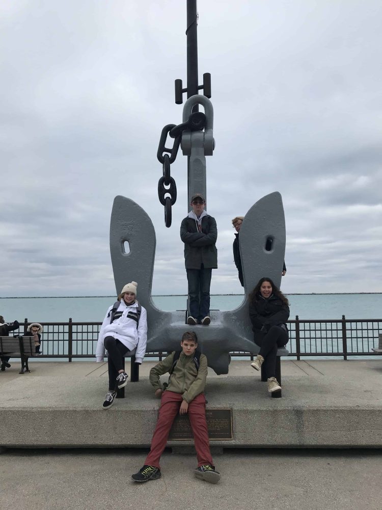 students on a sculpture of a boat anchor
