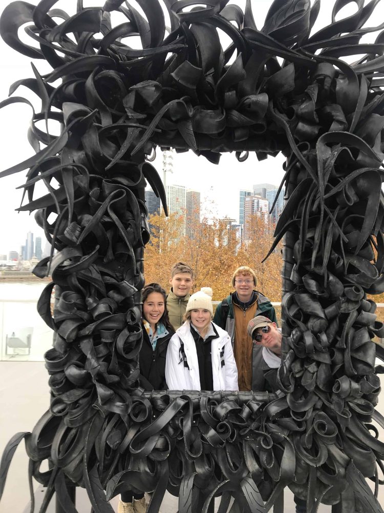 students behind a picture frame sculpture