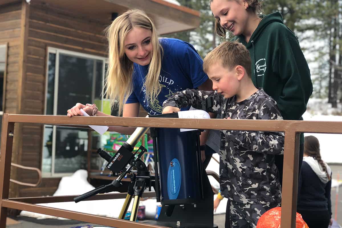 students standing around a telescope outside