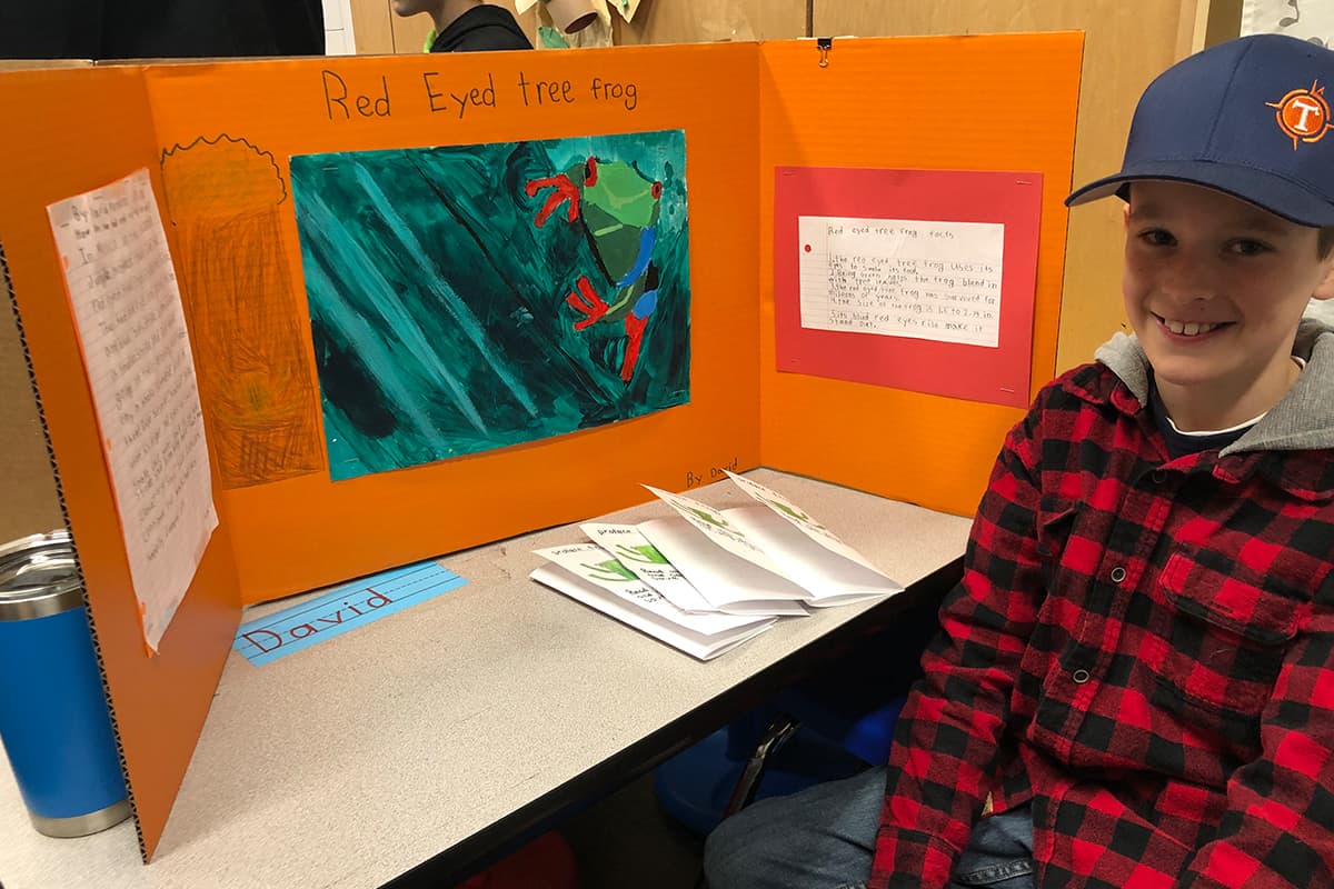 a boy stands next to his red eyed tree frog storyboard