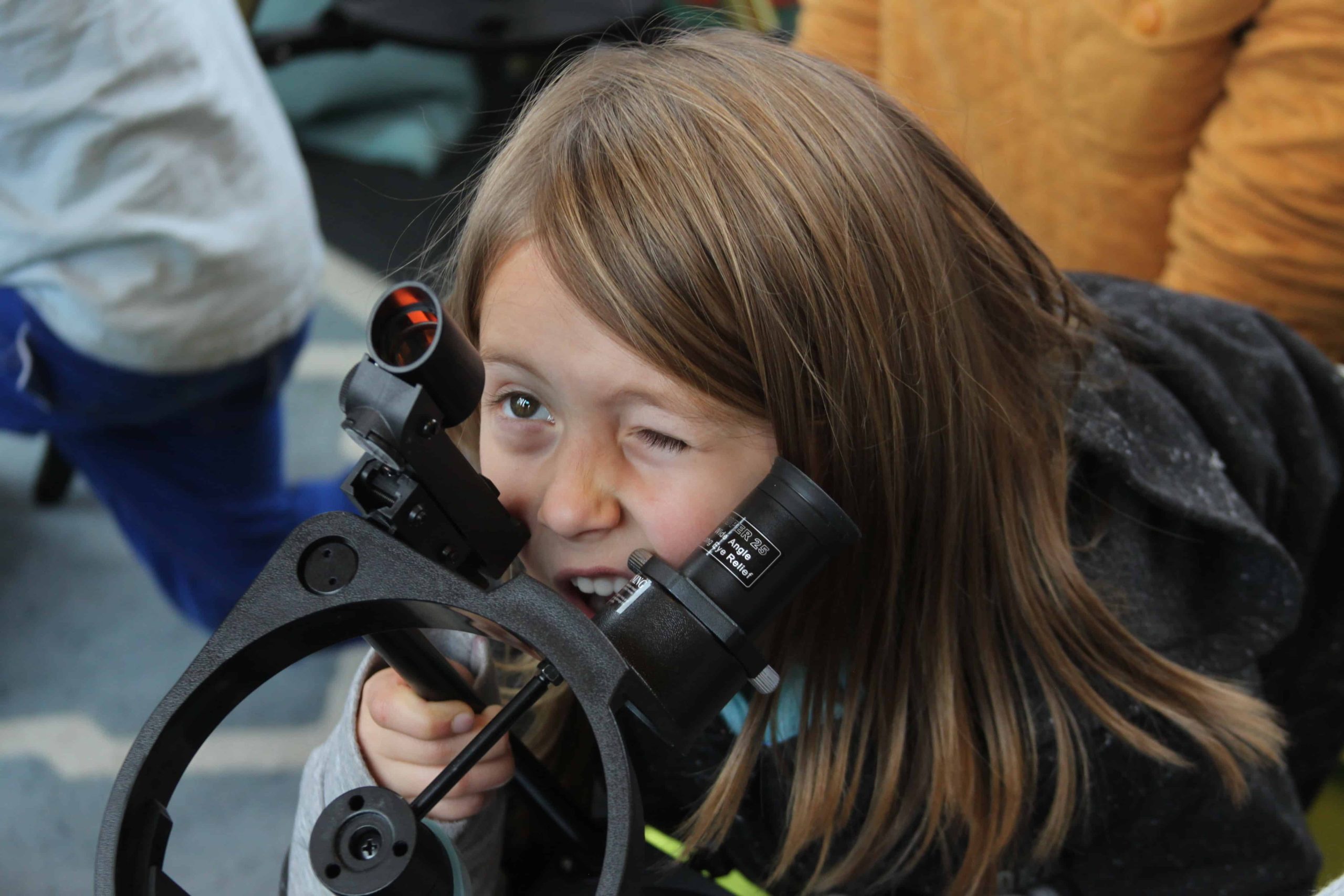 a girl looking through a telescope sight