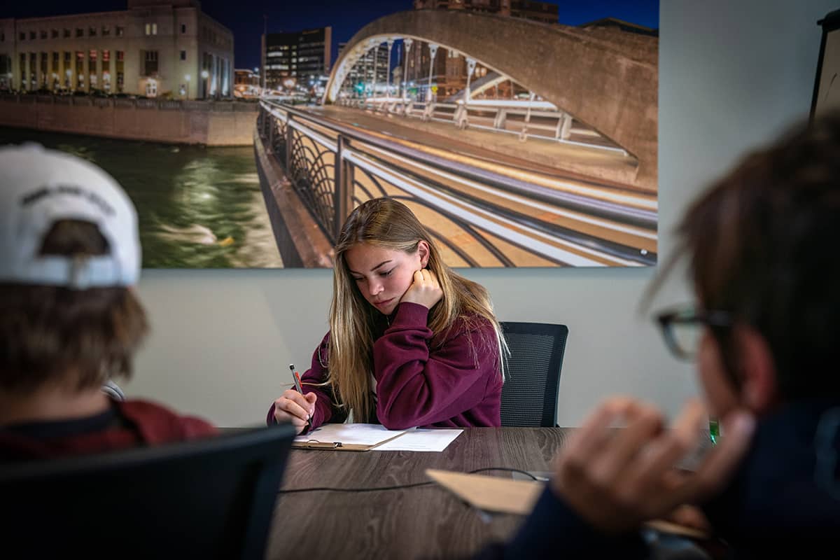 a girl sitting at a table taking notes