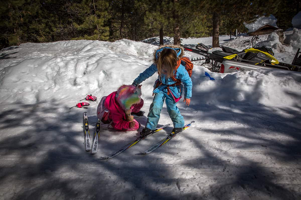 a student helps her classmate put on skis