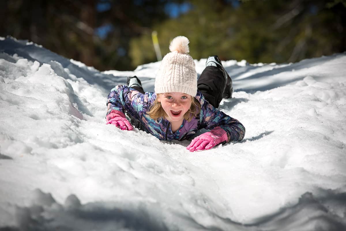 a girl sliding down a snowy hill