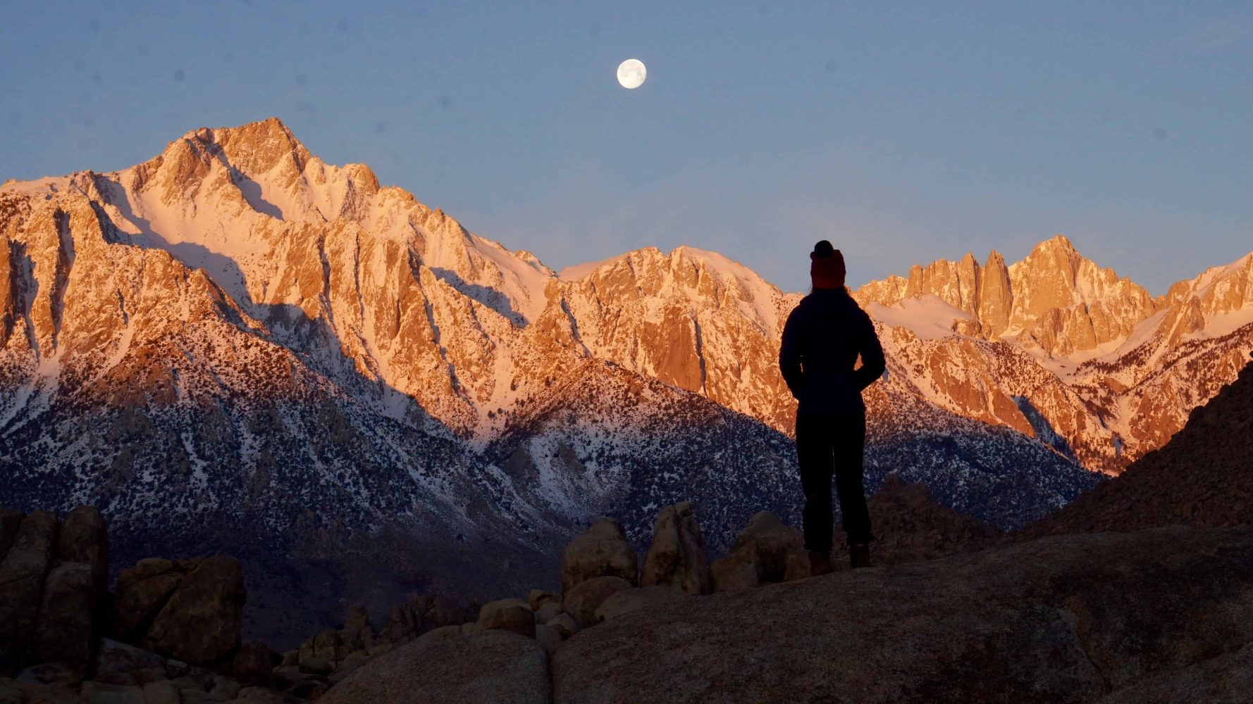 student watching the sun set across the mountains