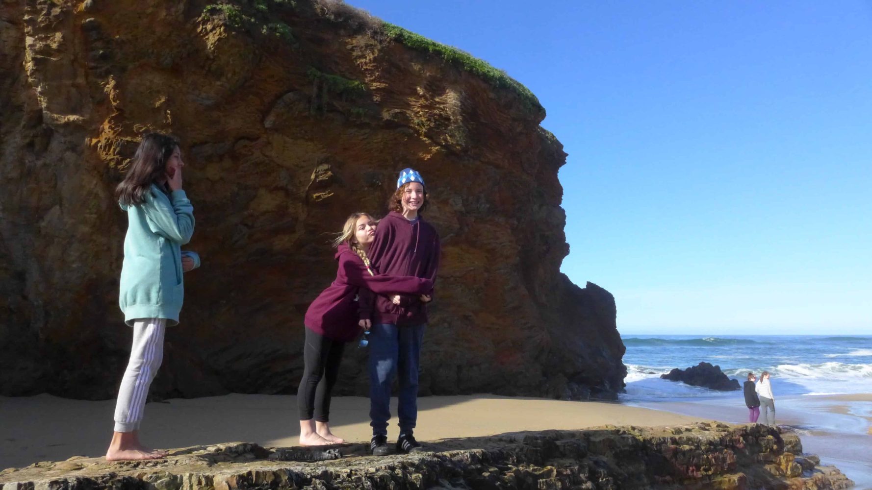 a girl hugging her friend next to the beach