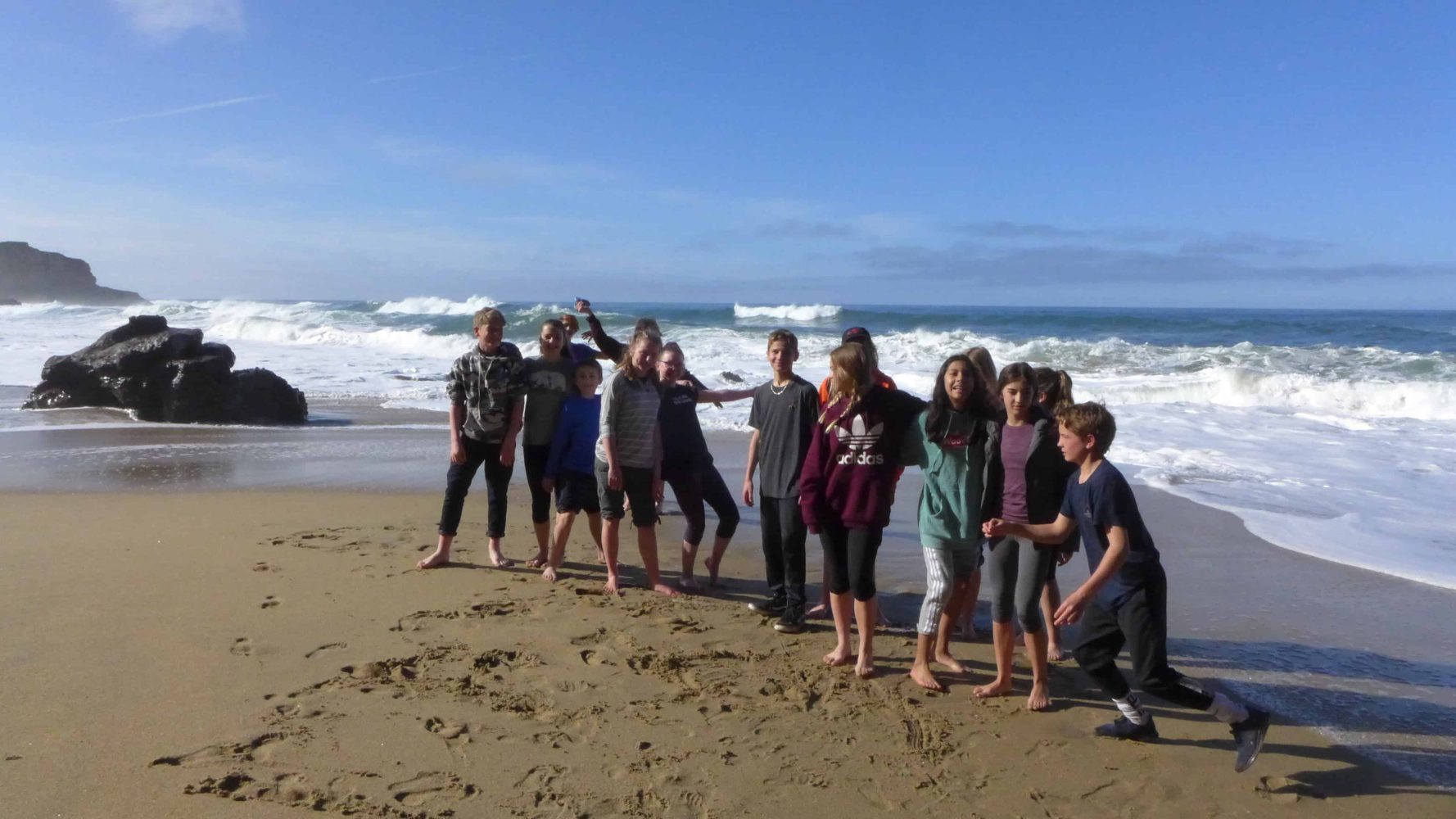 students posing for a picture in front of the ocean
