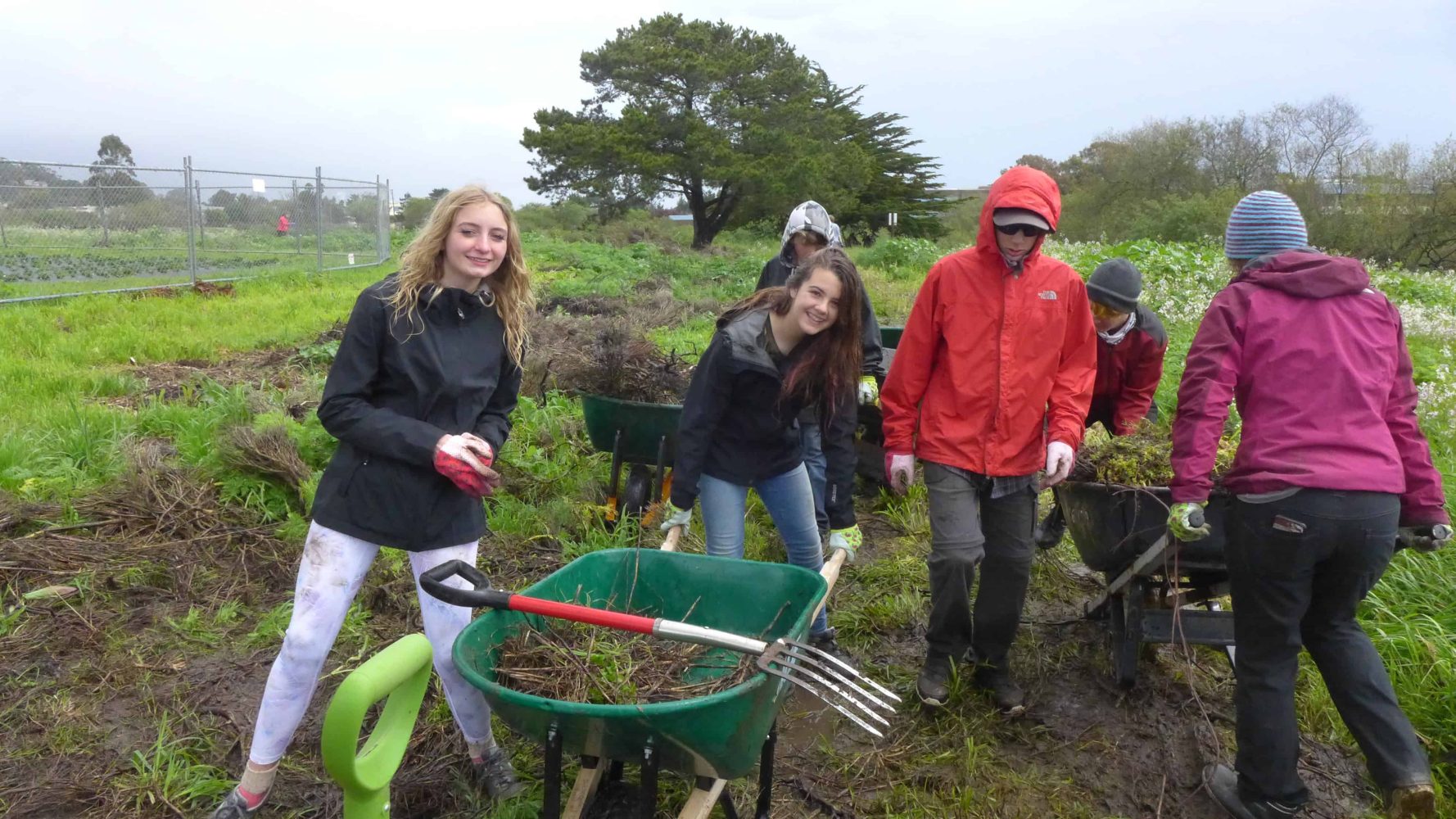 students in a field with gardening tools
