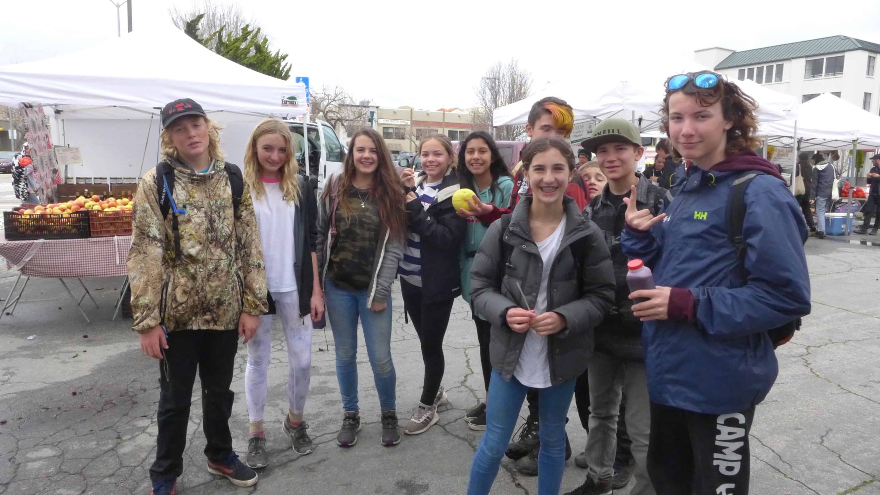 stends standing in front of fruit and vegetable stalls