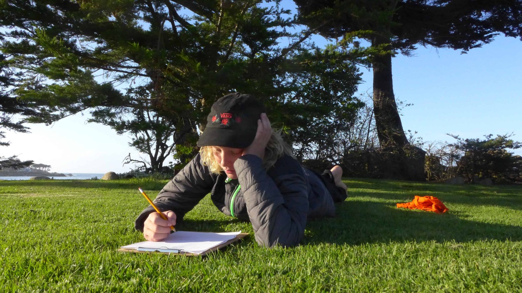 a student taking notes while laying in the grass