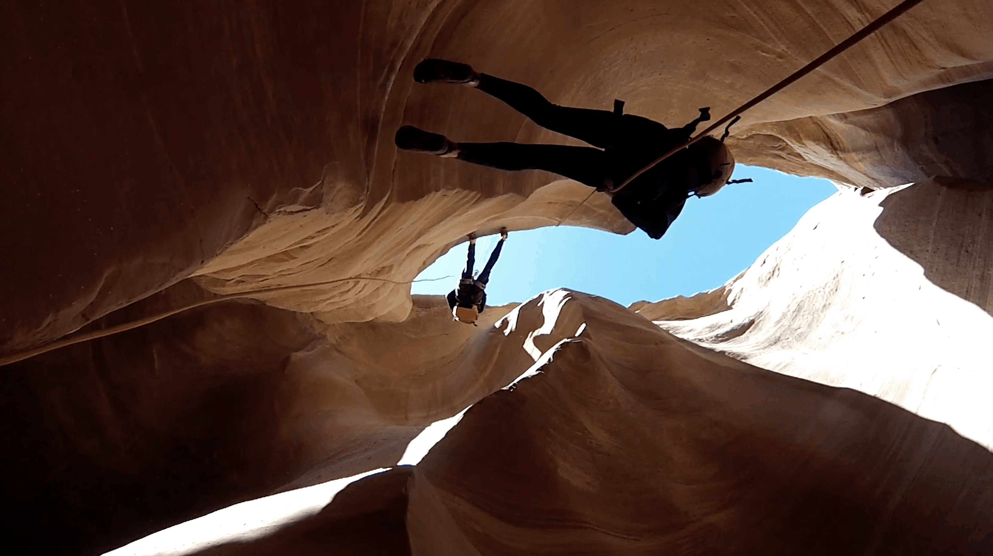 students on rope harnesses climbing up a ravine