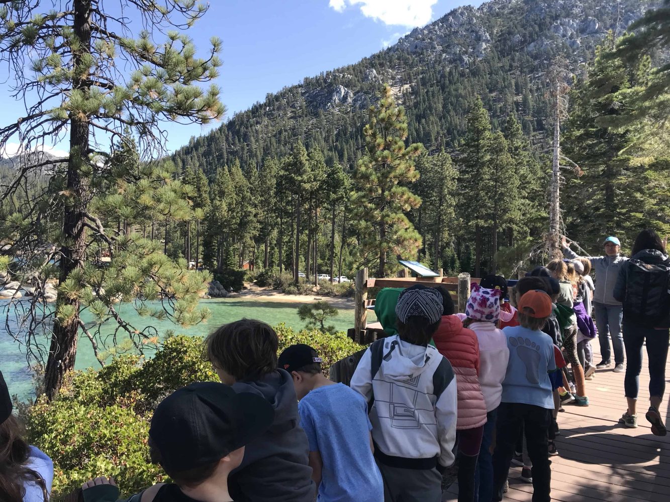 students walk on a trail beside the lake