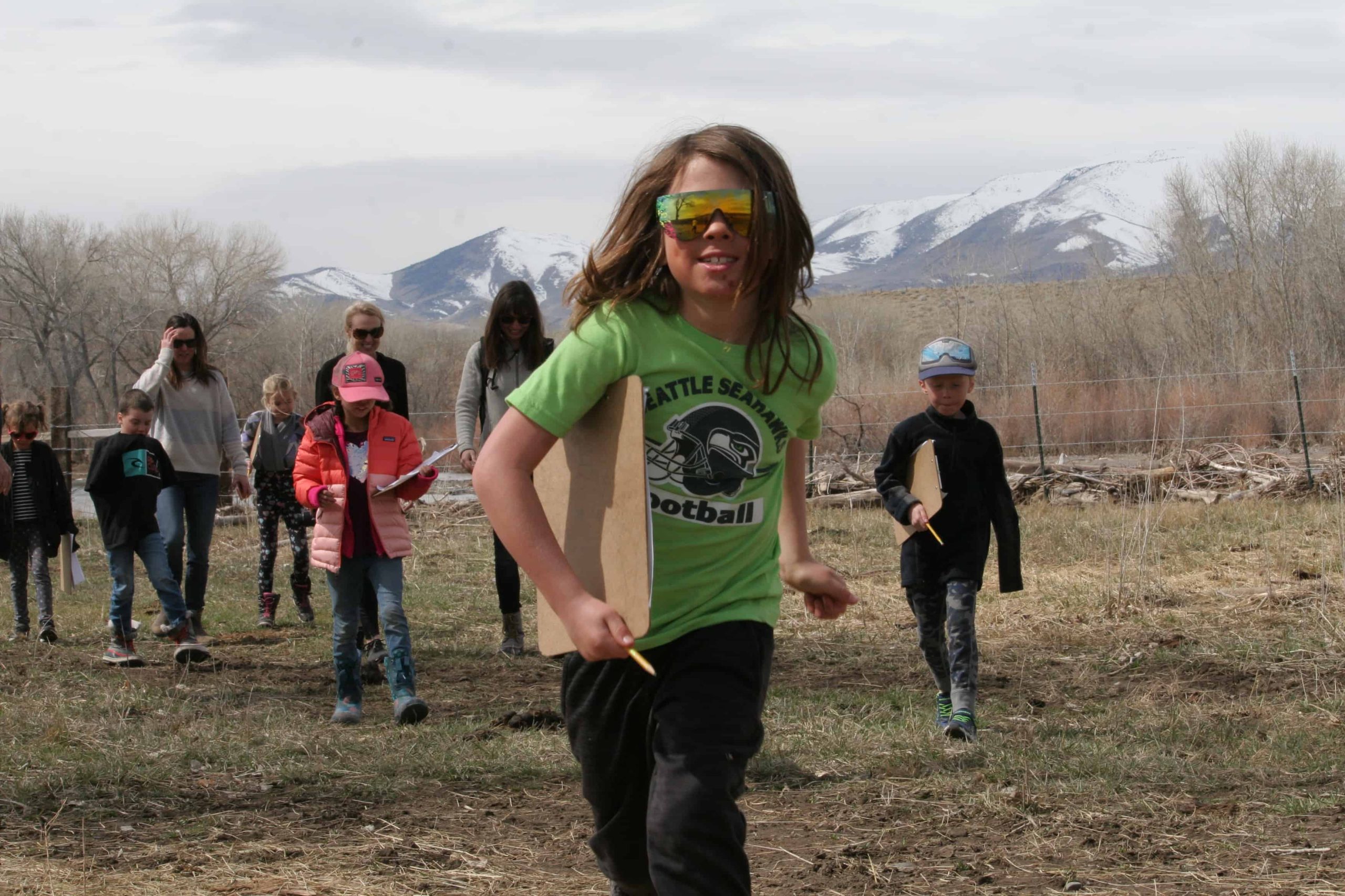 students with clipboards walking with their teacher