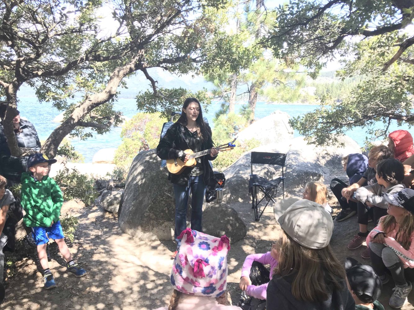 students listen to a woman playing guitar