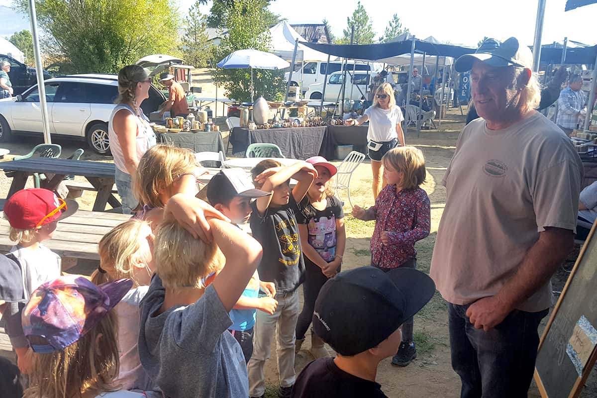 students gathered around a farmer