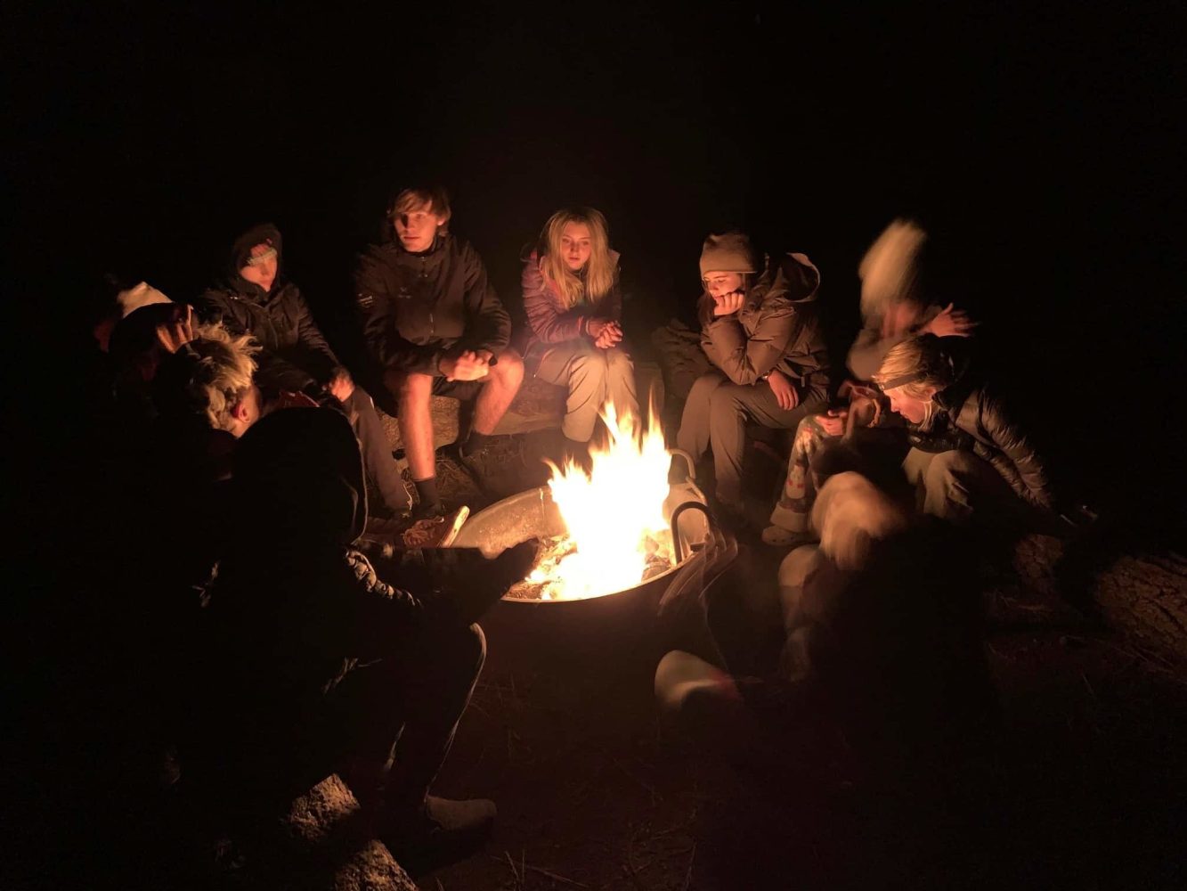 kids sitting around a campfire at night