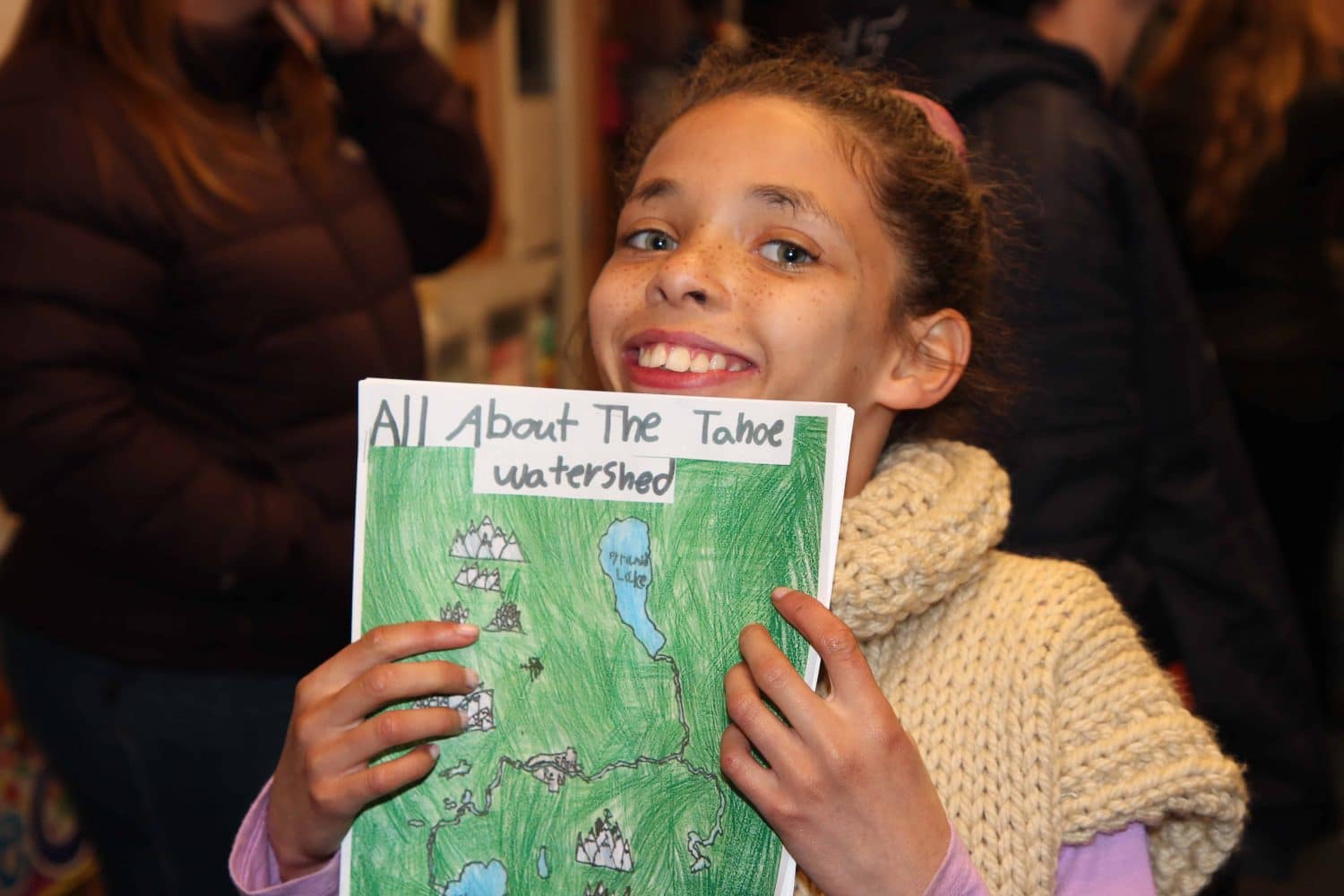 a student holding her all about the tahoe watershed report