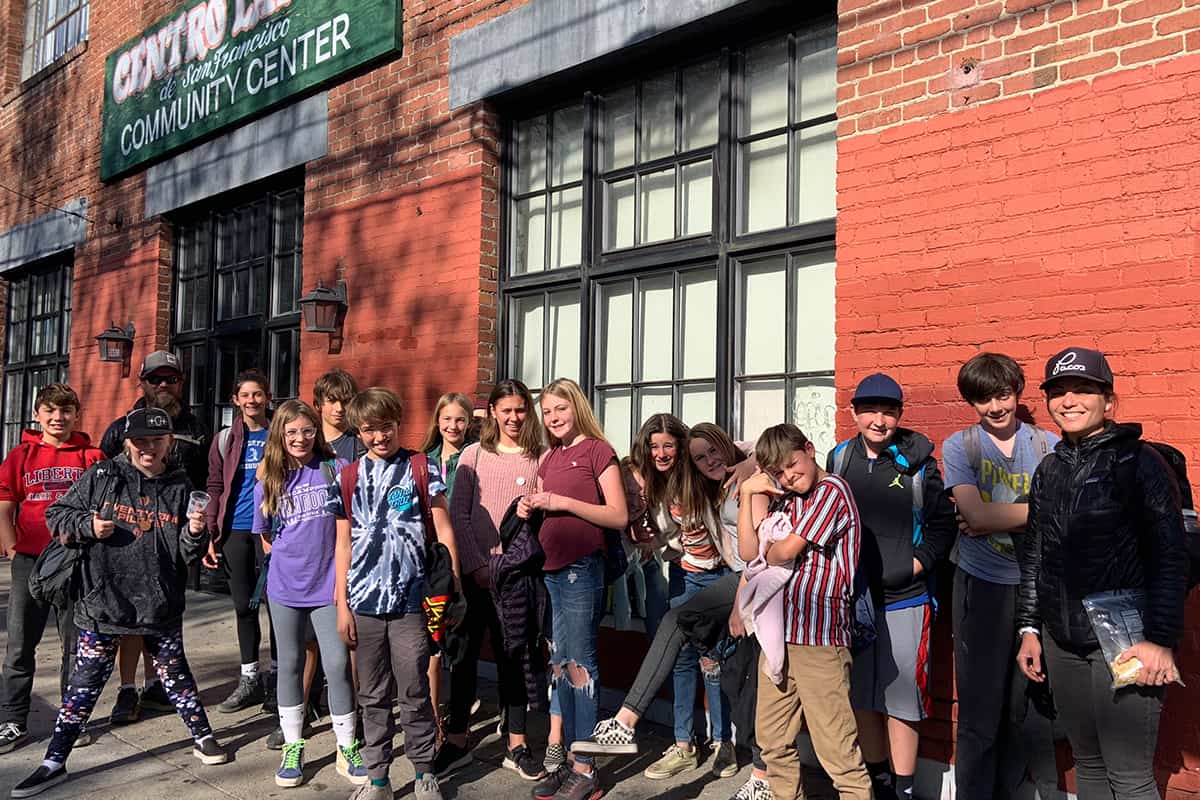 TEA students pose in front of a community center