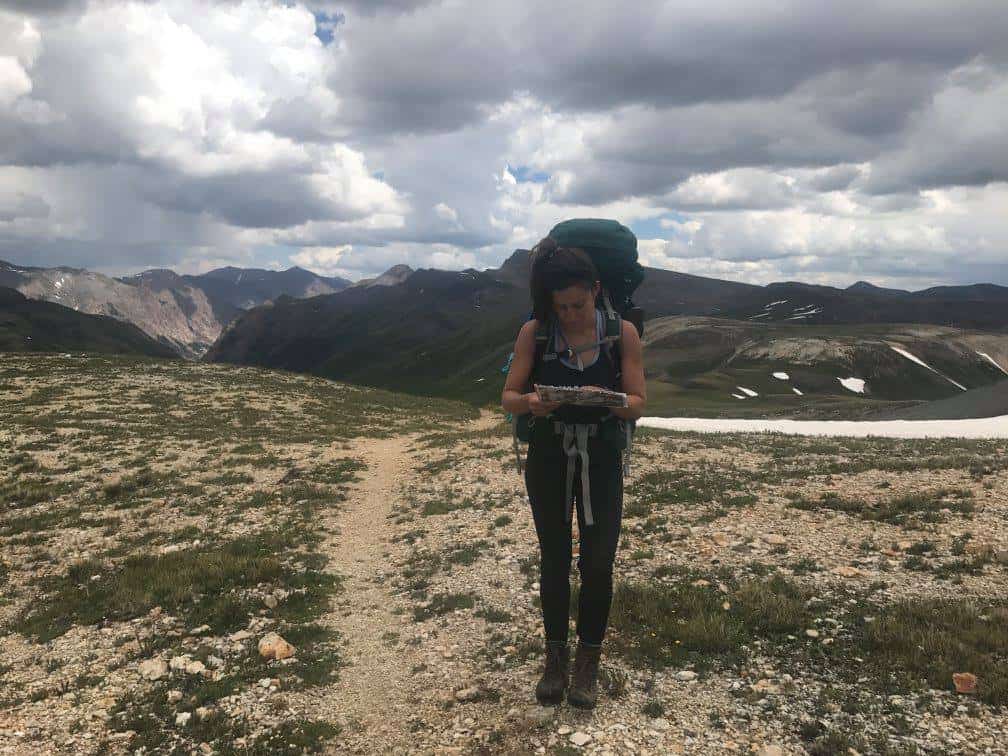 a woman with camping gear reading a map