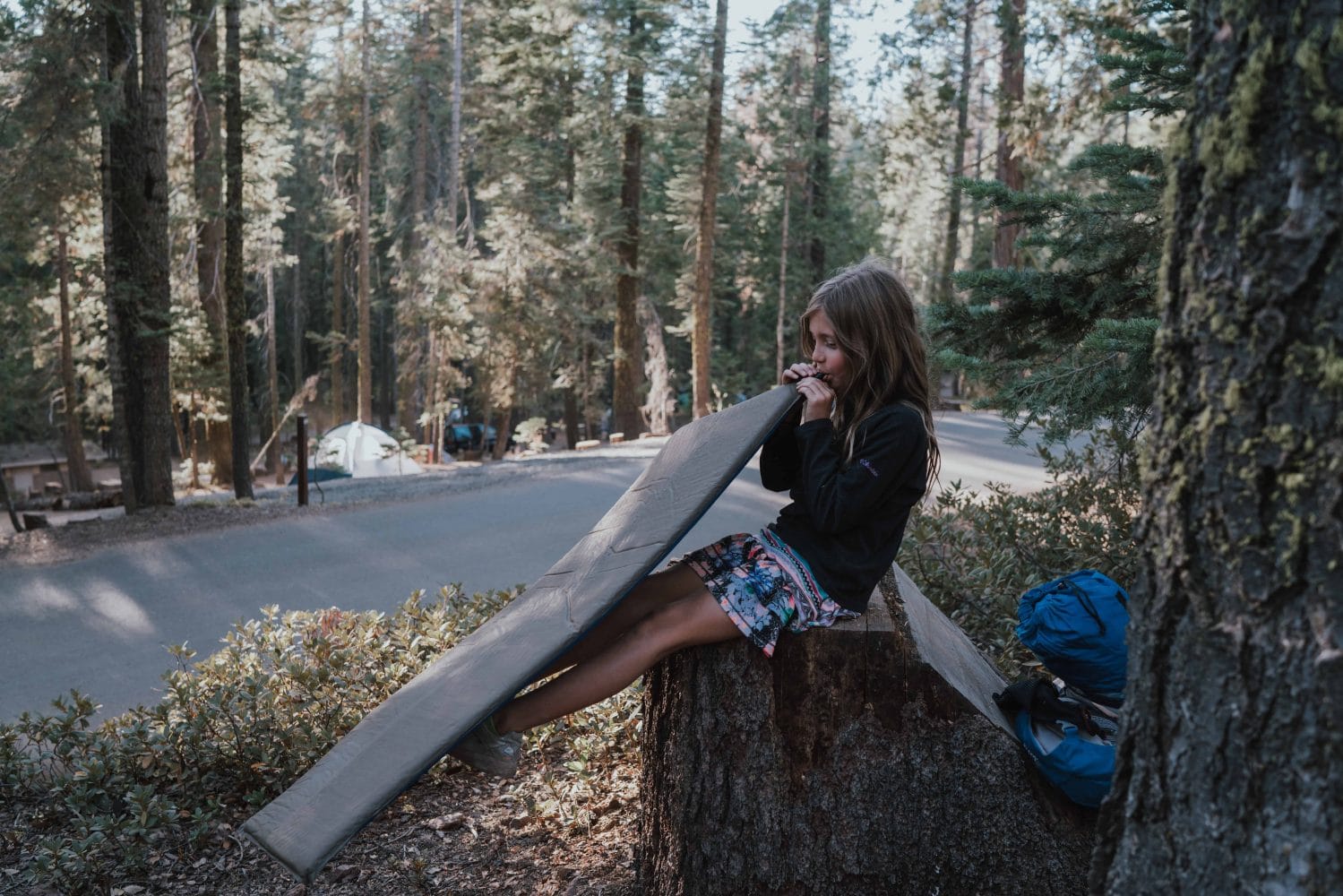 5th grader sits on a log and unpacks