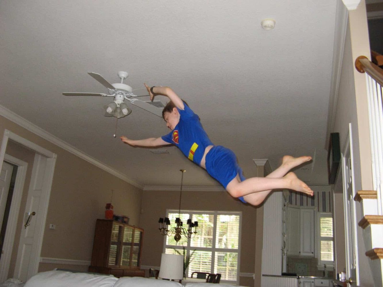 kid with superman shirt jumping onto a couch