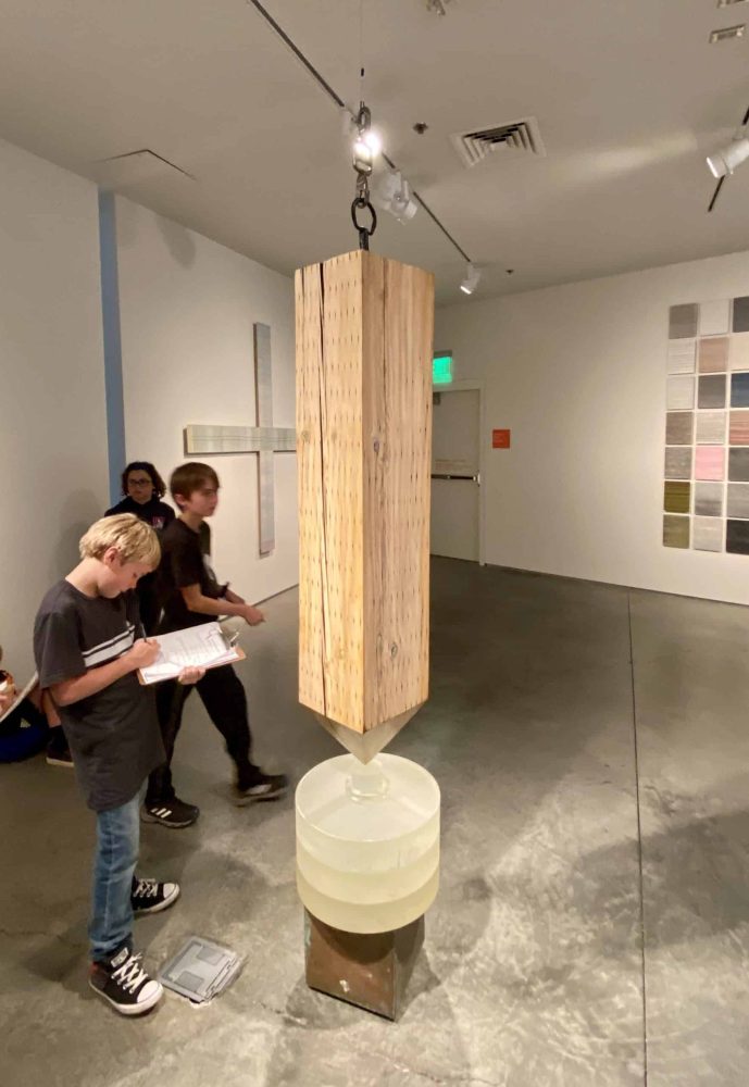 A 5th grader taking notes in front of an art installation